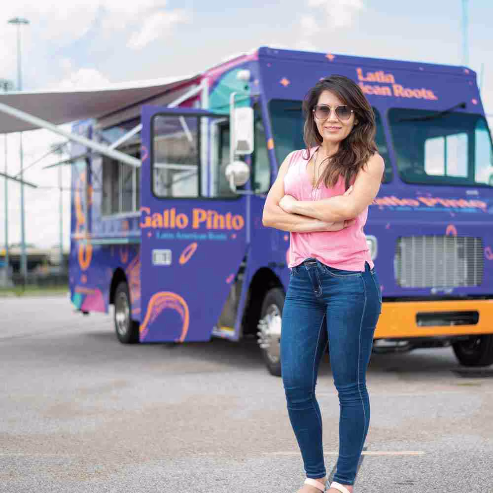 Owner standing in front of their custom-built food truck with a vibrant purple vinyl wrap.