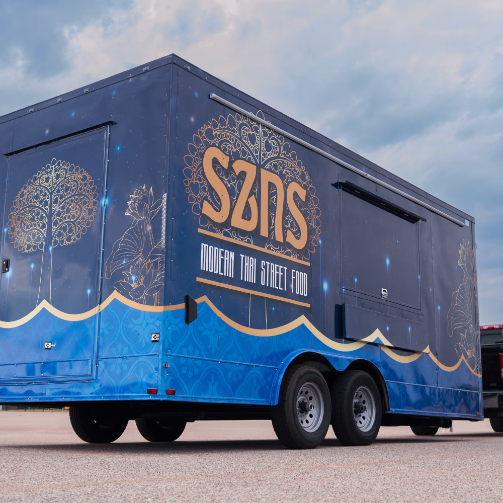 Custom-built food trailer with a blue vinyl wrap and gold lettering.